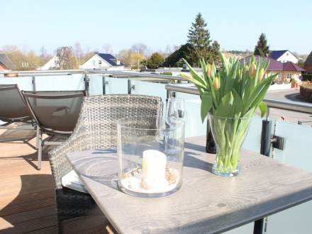 Balkon mit dekoriertem Tisch, Tulpen und Windglas mit Kerze